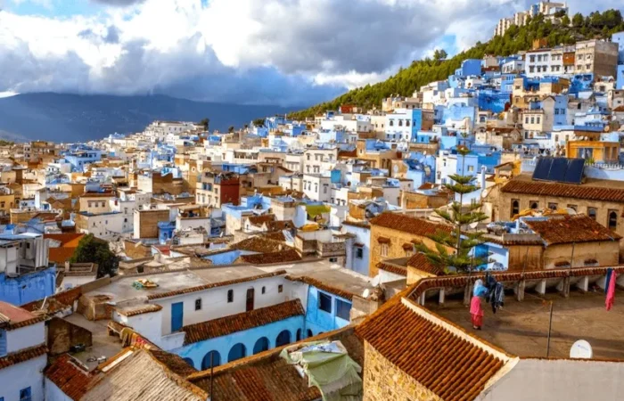 Scenic view of Chefchaouen, Morocco, showcasing its iconic blue buildings and mountainous backdrop under a clear sky.