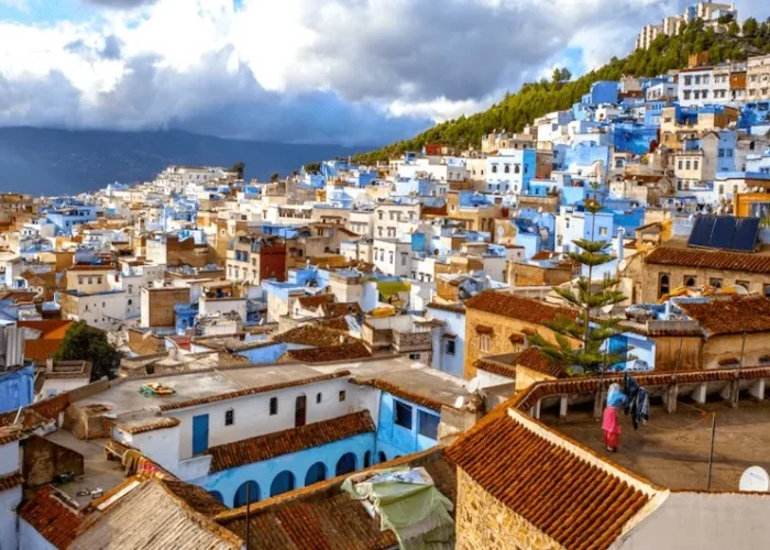 Scenic view of Chefchaouen, Morocco, showcasing its iconic blue buildings and mountainous backdrop under a clear sky.