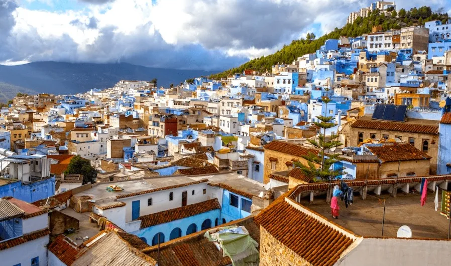 Scenic view of Chefchaouen, Morocco, showcasing its iconic blue buildings and mountainous backdrop under a clear sky.