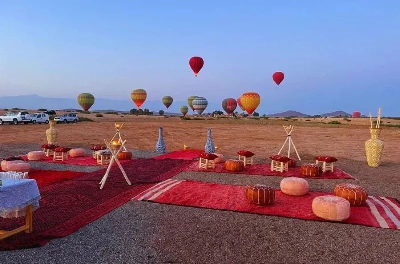 Colorful hot air balloons soar over a vast desert landscape in Morocco, showcasing a scenic balloon ride experience.