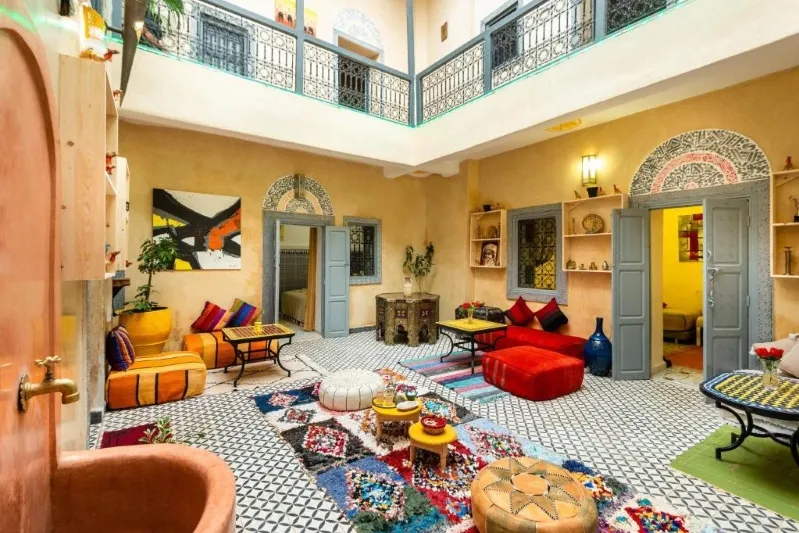 A vibrant living room featuring a colorful rug and stylish furniture, showcasing luxury and comfort in a Moroccan setting.