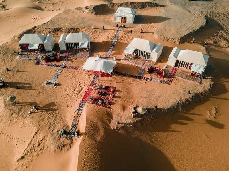 Aerial perspective of a Luxury Morocco desert camp, highlighting tents arranged in a serene desert environment.